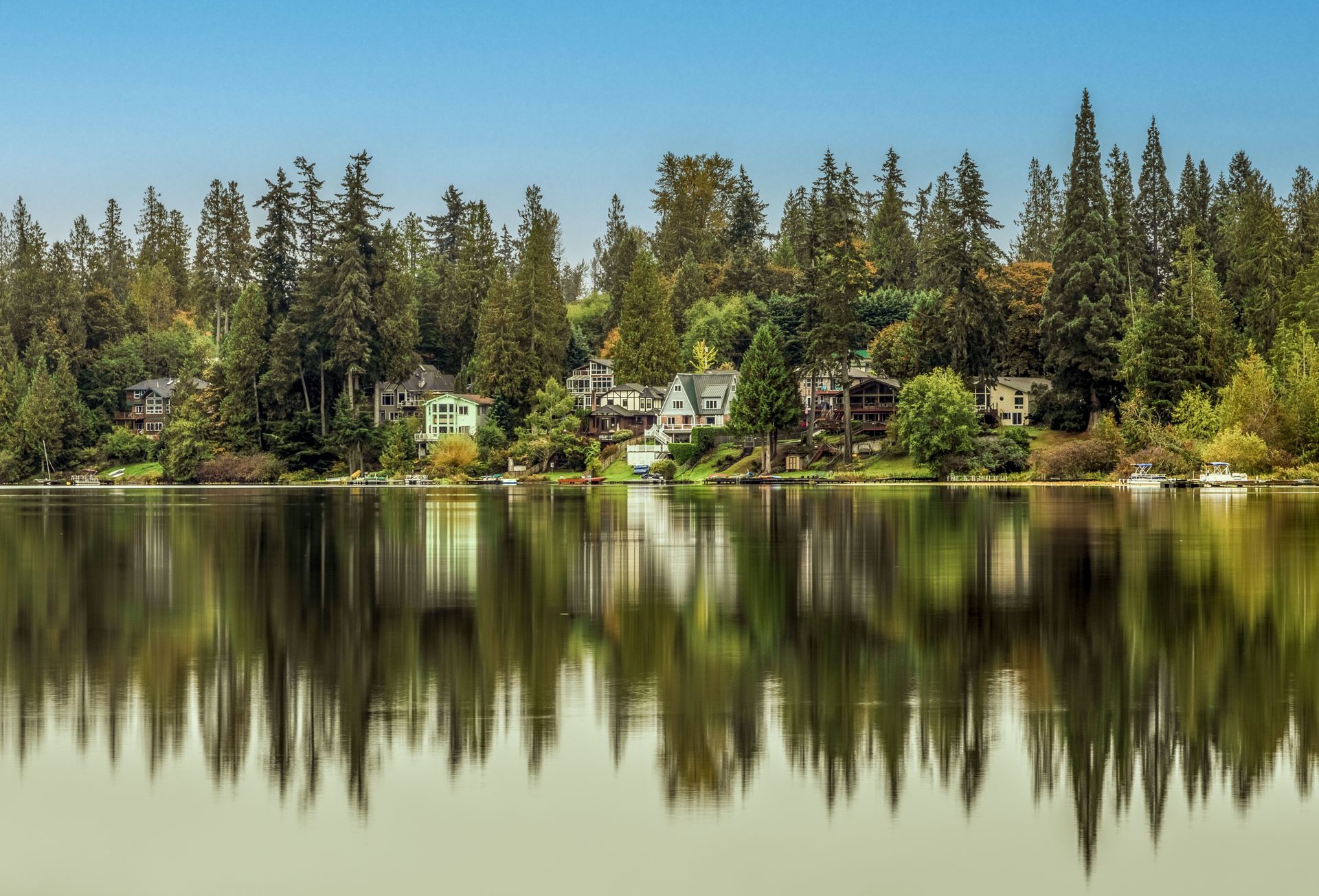 Lakefront homes and evergreens reflected in still water north of Seattle, Washington